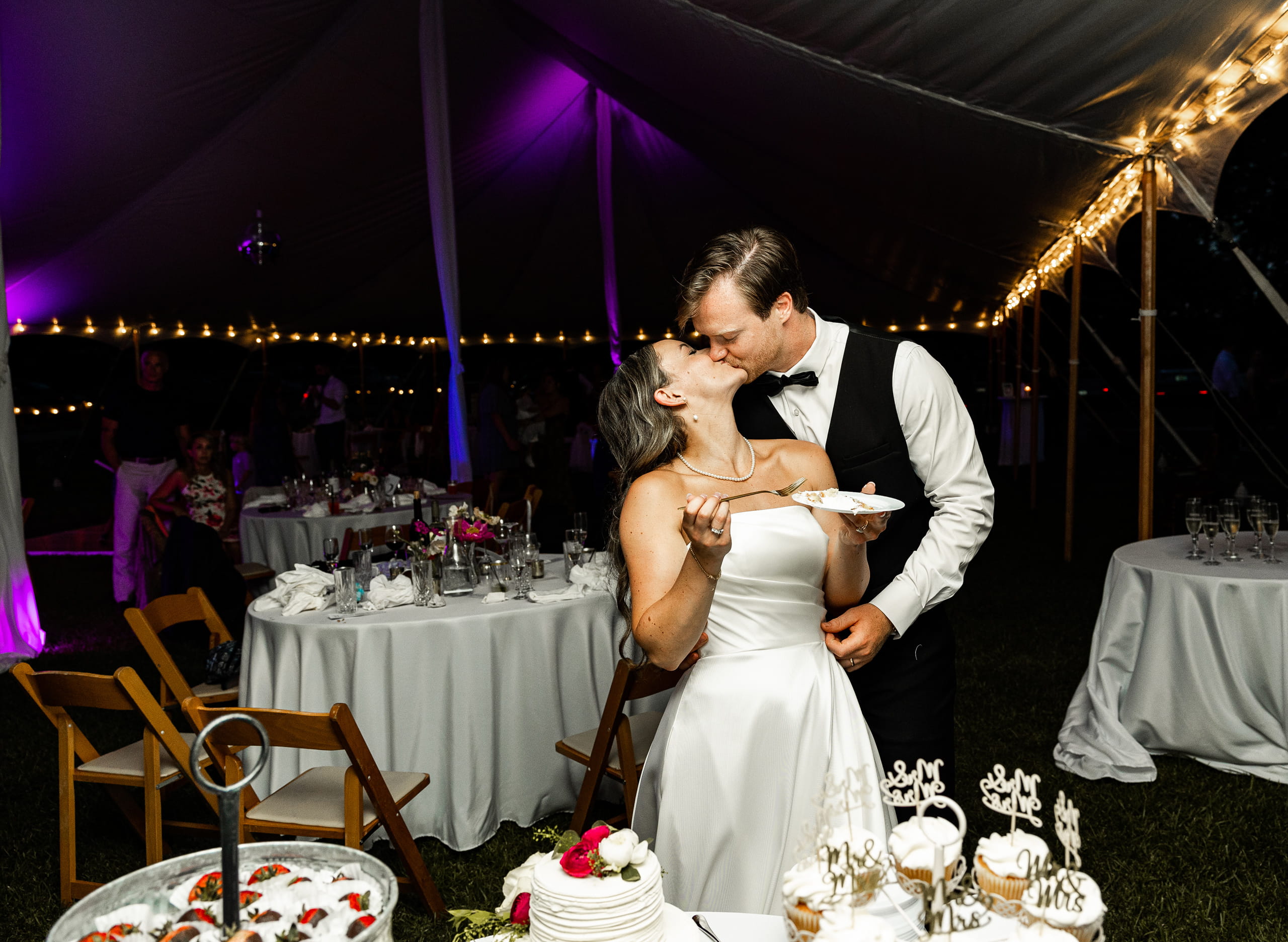 Andrew and Alyssa kissing during the wedding cake ceremony, a romantic and joyful moment.