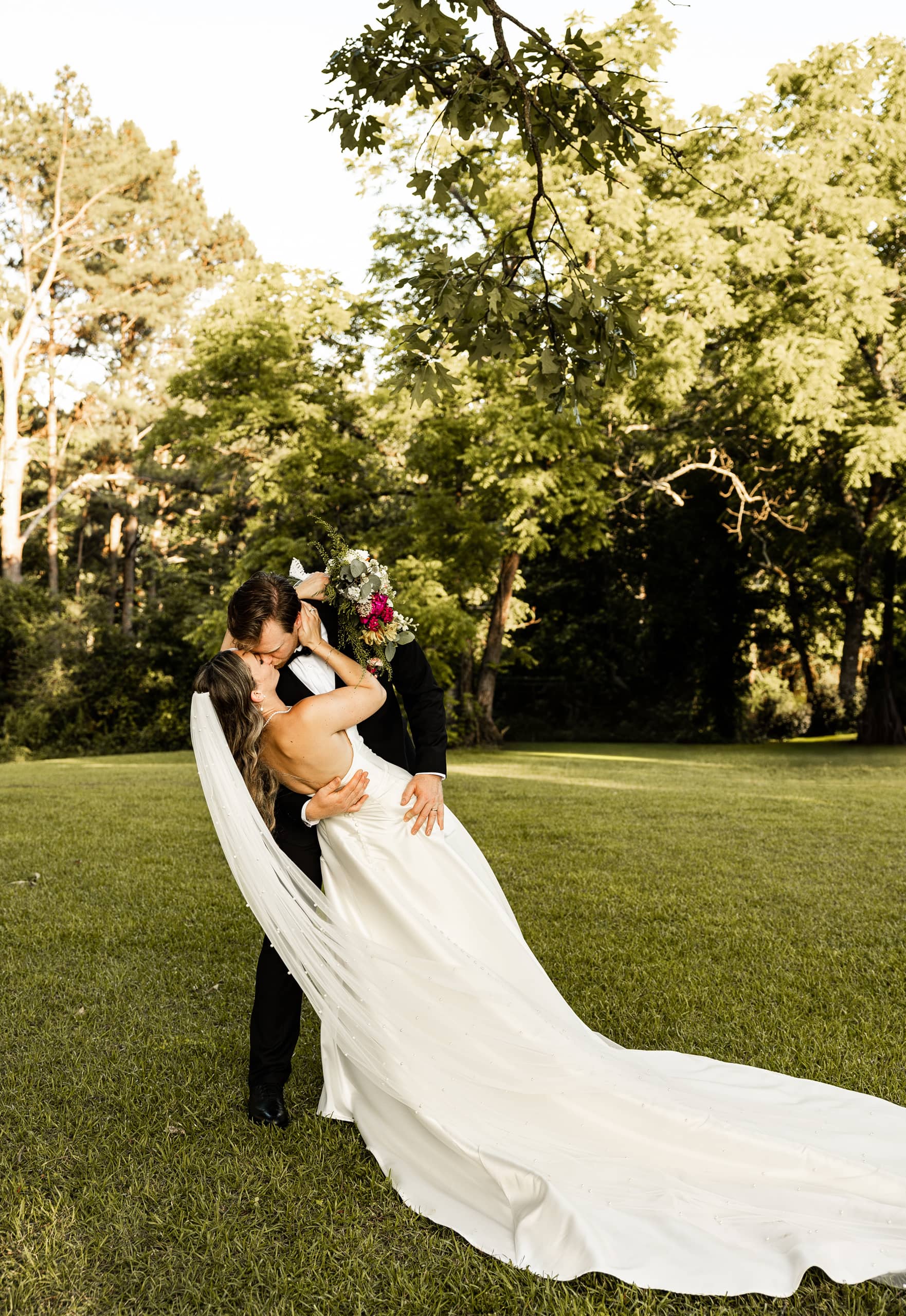 Andrew holding Alyssa in his arms and leaning her back as they share a passionate kiss, capturing a tender and cinematic wedding moment.
