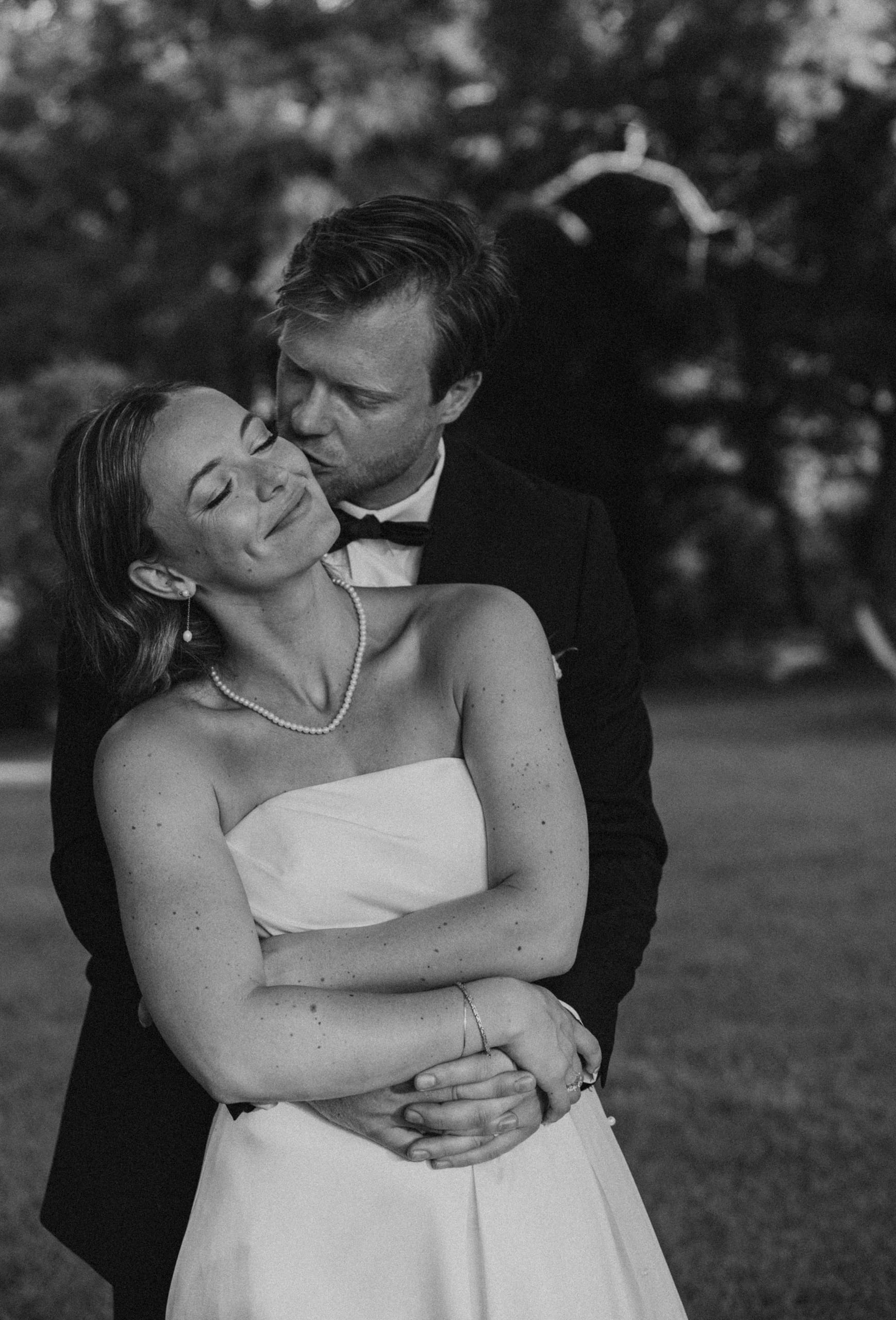 Artistic black and white portrait of the newlyweds, Andrew and Alyssa, embracing and enjoying their first moments together as a married couple.