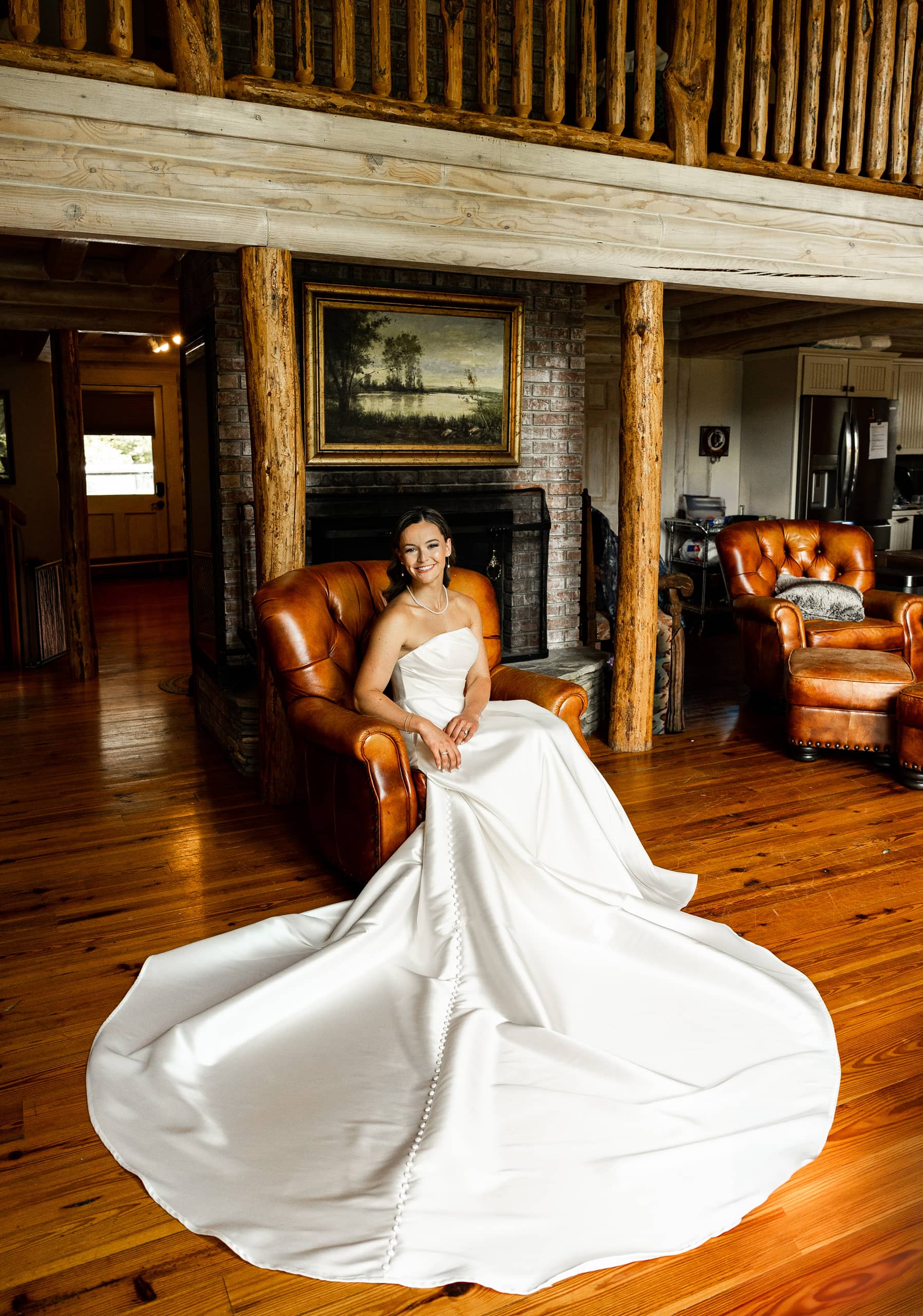 Bride sitting in a brown armchair in the lounge, showcasing her elegant wedding dress in all its splendor.