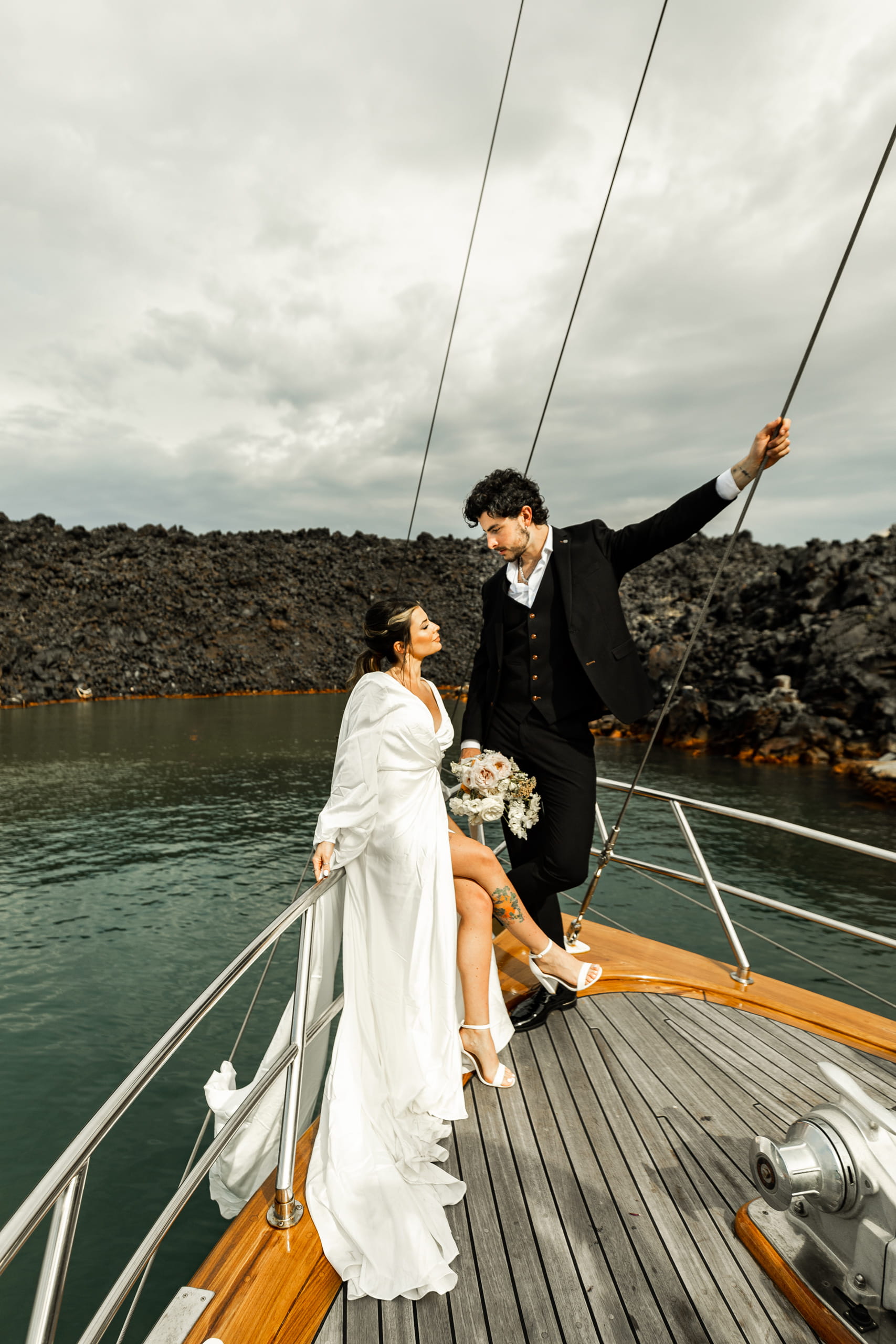 Romantic moment of Jeannie and Matty embracing on deck, volcanic cliffs towering behind them in the heart of the Aegean Sea.