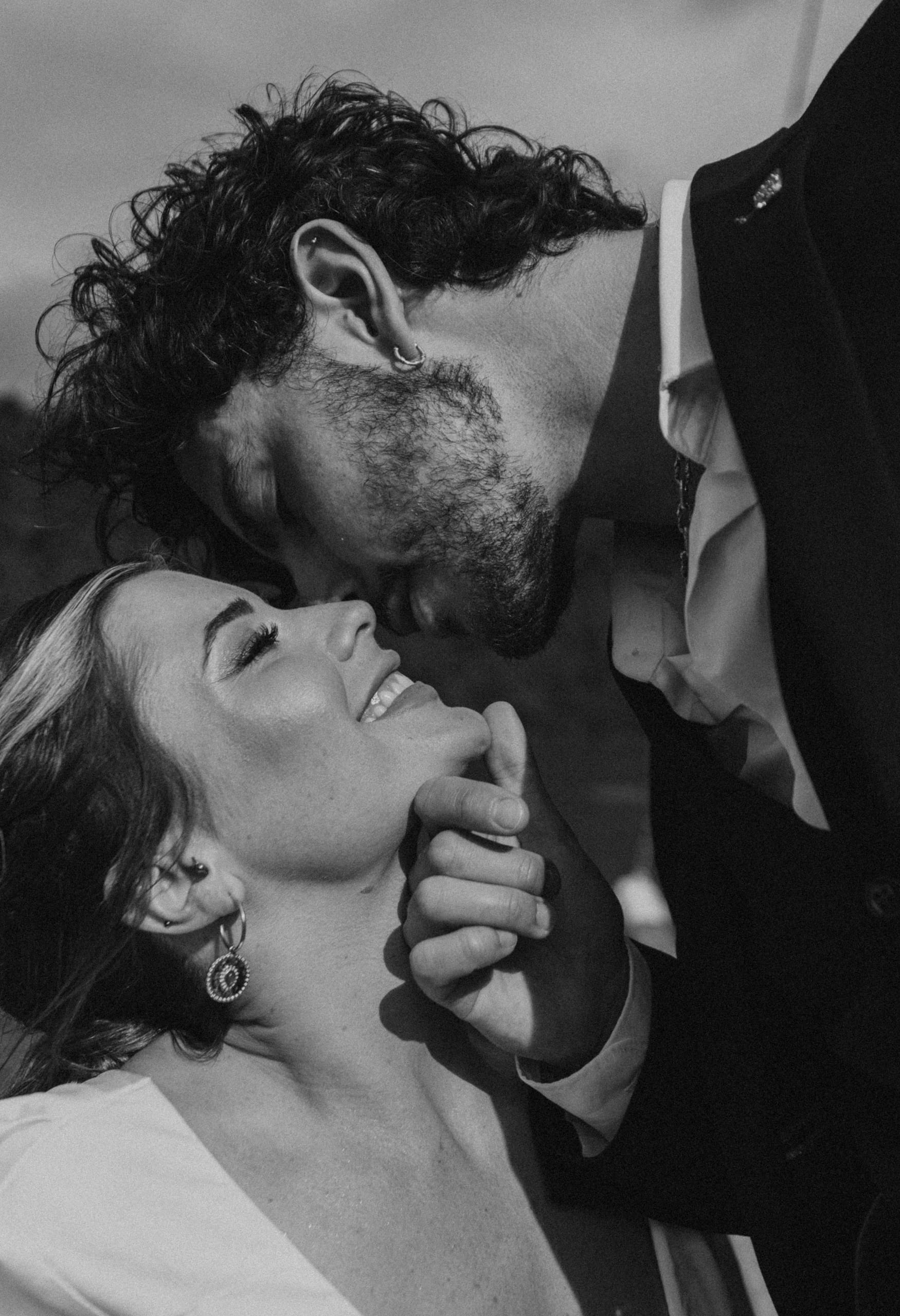 Candid black and white photo of Matty leaning toward Jeannie for a kiss, a timeless and emotional wedding moment on the Aegean Sea.